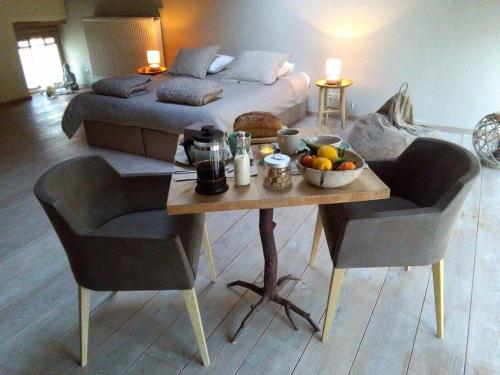 Un dormitorio con una cama y una mesa con un bol de fruta en Le Temps d'une Pause, en Ny
