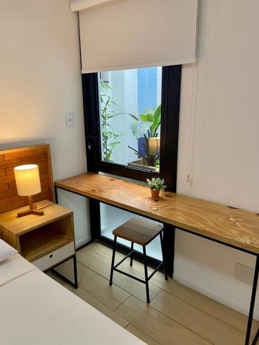 a desk in a room with a window with a plant at Requinte Hotel in São Paulo
