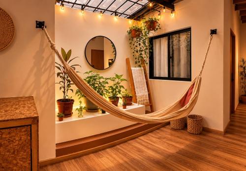a hammock in a room with plants and a mirror at Luum Guest House Manila in Medellín