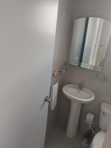 a bathroom with a sink and a toilet and a mirror at Rinconcito Caribeno Apartment in San Pedro de Macorís