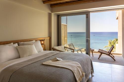 a bedroom with a bed and a view of the ocean at Pefkian Ethos Hotel & Suites in Pefki