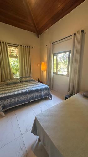 a bedroom with two beds and two windows at A Casa da lua in Lagoa Santa