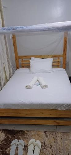 a bed with two pairs of slippers on it at Chateau Haven in Kakamega