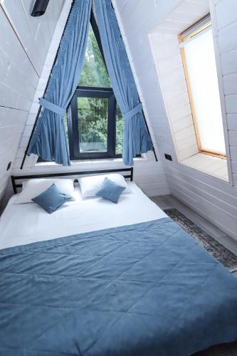 a bedroom with a large bed with blue curtains at A-frame cottage in Mykulychyn