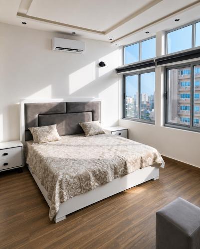 a white bedroom with a large bed and windows at Appartement à Cotonou in Cotonou