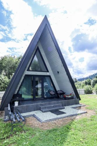 a triangular house with a window in a field at A-frame cottage in Mykulychyn