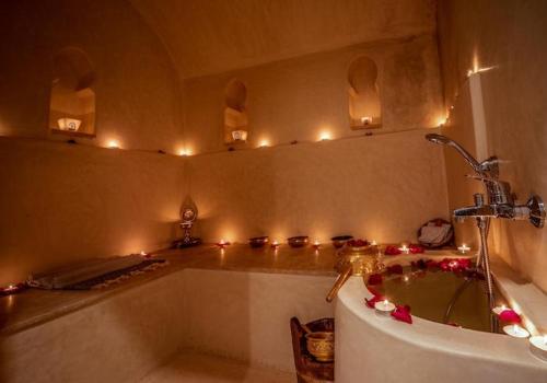 a bathroom with a tub with lights on the wall at Riad Le Sultan Rouge And Spa in Marrakesh