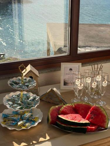 a table with a plate of watermelon and wine glasses at Vikendica Jablaničko jezero in Jablanica