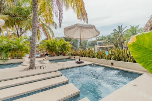 ein Swimmingpool mit Sonnenschirm und Palmen in der Unterkunft Tay Beach Hotel Tayrona in Buritaca
