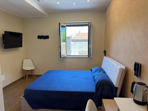 a bedroom with a blue bed and a window at La Stella dei Venti in Scilla
