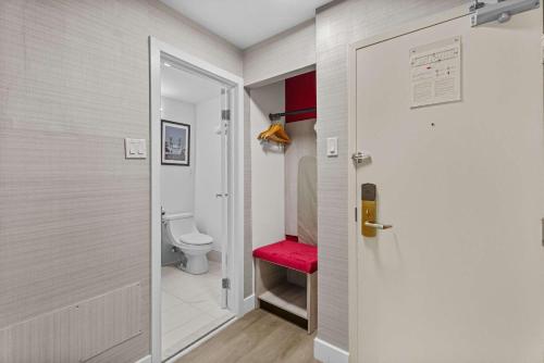 a small bathroom with a toilet and a red stool at Ramada Plaza by Wyndham Montreal in Montreal