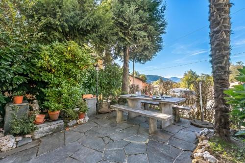 a picnic table in a garden with trees and plants at Casa Naima: Family House | Terrace & Peaceful Location - Happy Rentals in Breno