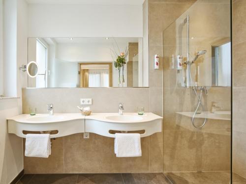 a bathroom with two sinks and a shower at Hotel Weis in Mertesdorf