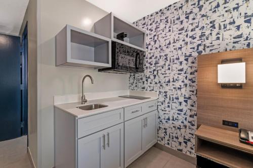 a kitchen with a sink and a tile wall at Red Lion Inn & Suites Kansas City in Kansas City