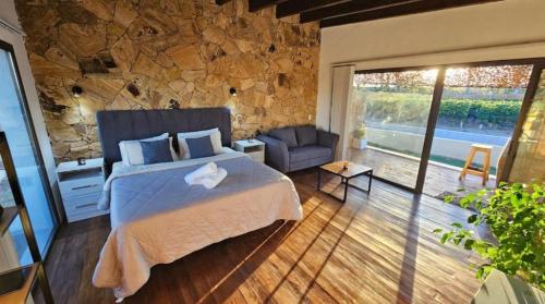 a bedroom with a bed and a stone wall at Rincon del Malbec 3 in Ciudad Lujan de Cuyo