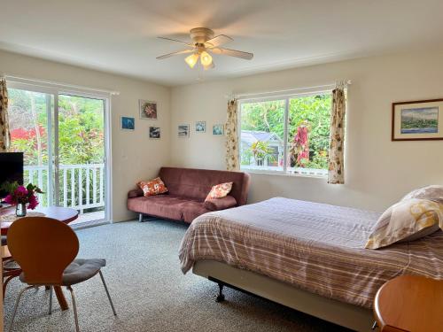 a bedroom with a bed and a couch and windows at Bears' Place Guest House in Kailua-Kona