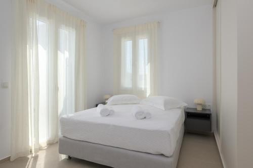 a white bedroom with a bed with two towels on it at Estia Villas Naxos in Naxos Chora