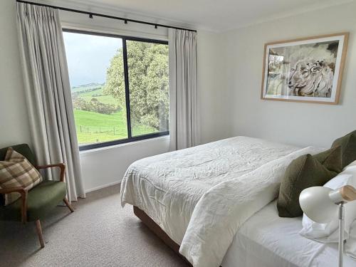 a bedroom with a bed and a window and a chair at Oak Vue cottage in Korumburra