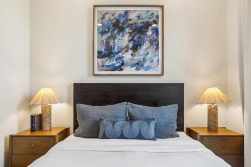 a bedroom with a bed with blue pillows and two lamps at 7BR City Condo & Pool Access Near CBD in New Orleans