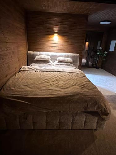 a large bed in a room with a wooden wall at Royal Ranch Nature Resort in Orhei