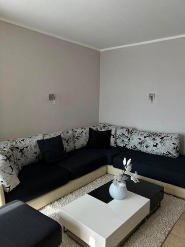 a living room with a black couch and a white table at Apartment golem in Durrës