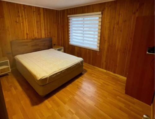 a bedroom with a bed and a window and wooden floors at Hospedaje Canarias in Pucón