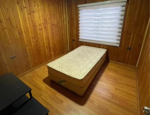 a small bed in a room with a window at Hospedaje Canarias in Pucón