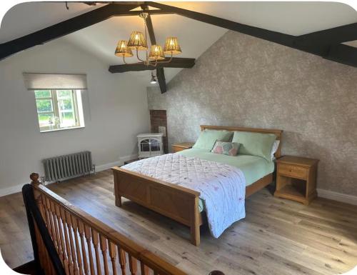 a bedroom with a bed and a wooden floor at The Hurst Stable Sleeps 4 with Hot Tub & Parking in Stafford