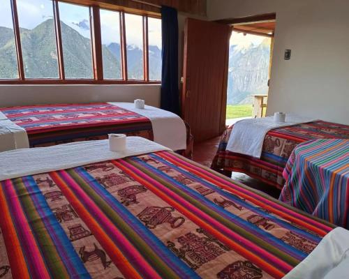 a room with three beds with mountains in the background at Llactapata Lodge overlooking Machu Picchu - camping - restaurant in Santa Teresa