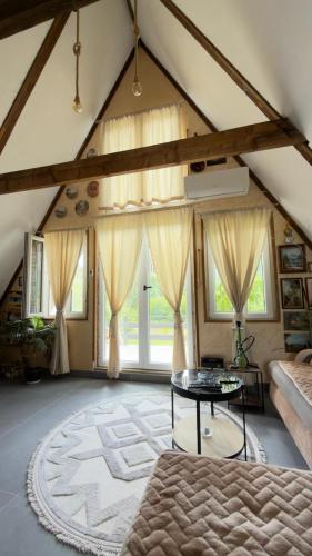 a large attic room with a table and some windows at Vrela Holiday Home in Cetinje