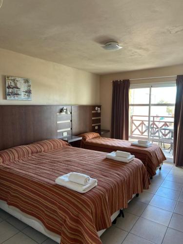 a hotel room with two beds and a balcony at Marchetti Hotel Comedor in Miramar