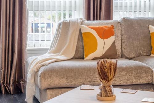 a living room with a couch with pillows and a table at Park View-modern 2 bed apartment in Motherwell
