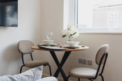 a table with two chairs and a table with flowers on it at The High Town Suite in Luton