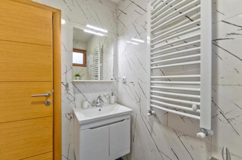a white bathroom with a sink and a mirror at Brvnara Mont 1 in Zlatibor