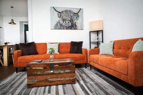 a living room with two orange couches and a table at Castle Grant - 4 Bed Cottage in Gardenstown in Gardenstown
