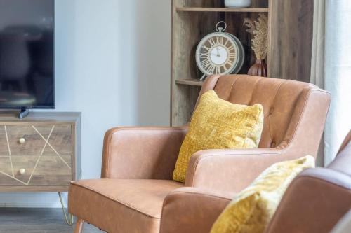 a brown chair with yellow pillows in a living room at Lendrick House-Spacious 3 Bed House in Falkirk in Polmont