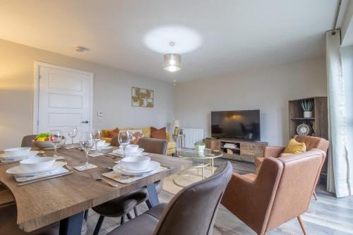 a dining room with a table with chairs and a television at Lendrick House-Spacious 3 Bed House in Falkirk in Polmont