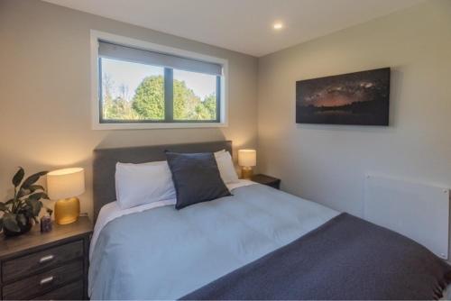 a bedroom with a bed with two lamps and a window at Whakatā in Te Anau