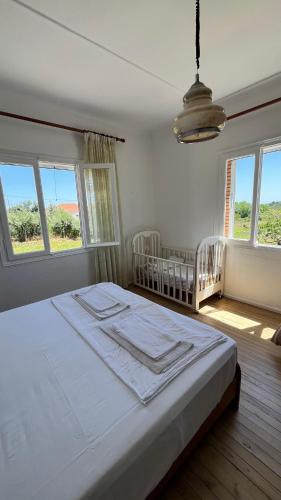 a white bedroom with two cribs and two windows at Avdera Holidays apartments in Ávdhira