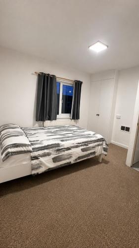 a bedroom with a large bed with a window at The Nest Chelmsford in Chelmsford