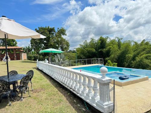 a swimming pool with a table and an umbrella at El Rincón del Sol y Luna in Quimbaya