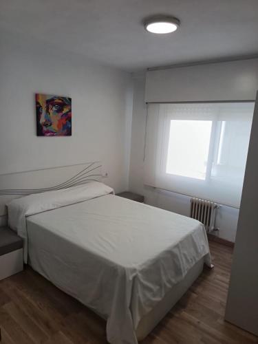 a bedroom with a white bed and a window at Piso vacacional YaraMaya in Carballino