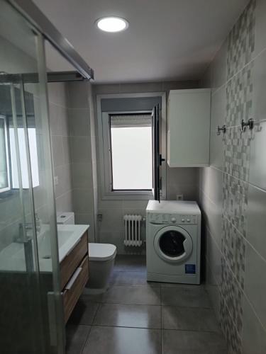 a bathroom with a washing machine and a toilet at Piso vacacional YaraMaya in Carballino