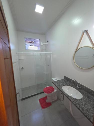 a bathroom with a sink and a toilet and a mirror at Pousada Canto do Sabiá in Piúma
