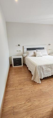 a white bedroom with a bed and a wooden floor at Casa Vilanova Costa da Morte in Cee