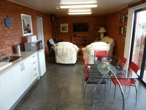 a kitchen with a glass table and red chairs at Panorama on Sorell B&B in Sorell