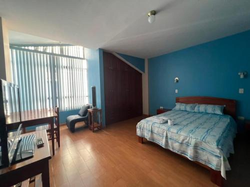 a bedroom with blue walls and a bed and a desk at Casa familiar D'Greta in San Ramón
