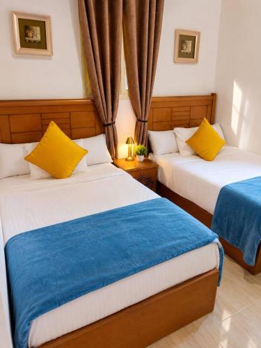 a bedroom with two beds with yellow and blue sheets at New Coast Chalets -K77 in Dawwār Muḩammad Abū Shunaynah