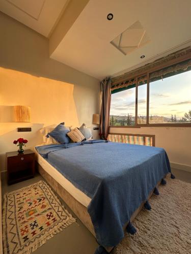 a bedroom with a bed and a large window at Jnane Ayam Atlas in Ourika