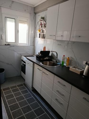 a kitchen with white cabinets and a sink and a stove at Apartment Olimp Ulcinj in Ulcinj